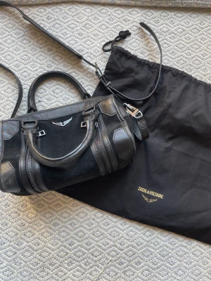 Zadig et Voltaire sunny bag mocka - Svart mocka väska ”Sunny Bag” ifrån Zadig et Voltaire. Dragkedjorna kan göra väskan större. I väldigt gott skick men har små tecken på användning som syns på bilderna. Dustbag medkommer Nypris: ca 4600kr och jag säljer för 2200kr