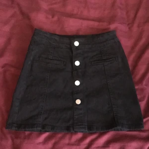 Jeanskjol  - Svart jeanskjol med knappar, lappen är borta men skulle säga att den är i strl xxs-xs. Säljer för att den inte passar längre :)