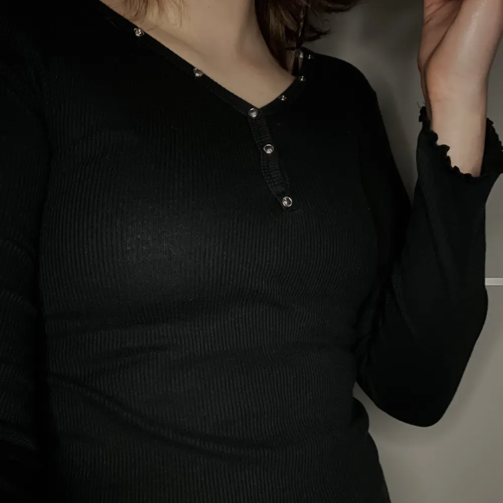 Långärmad svart tröja med knappar. Ribbat tyg och ”ruffled” sömmar vid ärmar och nedre kant. Jag tycker den är jättefin men den passar tyvärr inte mig längre, därför säljer jag den!. Toppar.