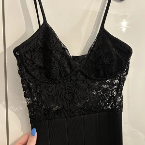 Svart klänning m spets överdel - Knälång klänning med spetsöverdel, inbyggda byglar och dragkedja i ryggen. Aldrig använd 