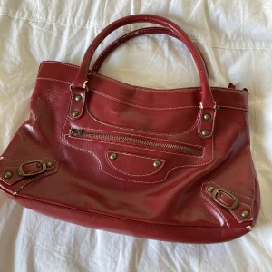 Röd skinnväska  - Skit snygg röd skinnväska köpt secondhand, bra skick men lite sliten på några få ställen. Går att ha som axelväska (se bild 2) Priset går att diskutera!!