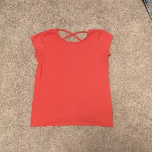 Jättefin T-shirt i en korallrosa färg. Har rors vid ryggen och är i nyskick. Storlek 170 från Linde kids