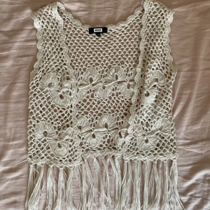 Vit virkad väst - Virkad liten väst med blommönster och fransar nedtill. Storlek xs, passar mig som brukar ha s-m. Kan mötas i närheten av Mariatorget eller posta. 