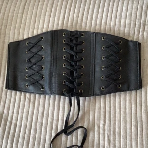 Bältes korsett - Snygg Bältes korsett.  Läder på framsidan och snörning. Baksidan är elastisk med tryckknappar. Köpt på Blue Fox.