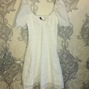 Kort H&M klänning  - Köptes men kom aldrig åt användning men annars perfekt för sommaren. Vit med blåa blommor 