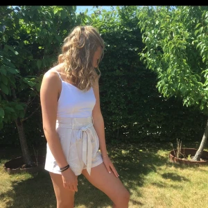 Jumpsuit - Vit linneliknande topp på och sen shortsen ljusbeigerosa med vita mönster som sitter ihop. Är så fin till sommaren.