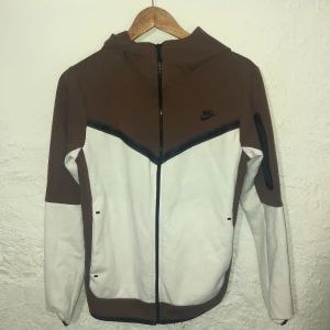 Brun och vit Nike tech - Fint brunt och vitt Nike tech, köptes på Plick för cirka månad sen och använt cirka 3 gånger. Inte äkta!