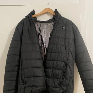 Jacka med Värmefunktion - En svart jacka med värmefunktion, upp till 3 olika värme nivåer Storlek L men passar även vissa med storlek M Knappt använd bara ett par gånger Funkar perfekt till vintern Pris kan diskuteras 