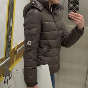 Moncler jacka - Fin moncler jacka som ej kommer till användning. Fint skick, några sömmar som har släppt ex tvättlapparna. Inget som stör funktionen. Annars är den felfri! Är osäker på om det är äkta då jag fått den av en bekant. Den är nytvättad. Brun/beige färg