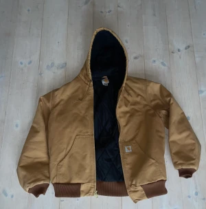 Jacka Carhartt - Varm vinterjacka i vattenavvisande ”cotton duck”. Köpt i Chicago för ca 4 år sedan och sparsamt använd. Storlek M men passar mer som en L.  Högst bjudande  Från Carharts hemsida: ”LOOSE FIT FIRM DUCK INSULATED FLANNEL-LINED ACTIVE JAC - 3 WARMEST RATING” 