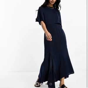 Marinblå midiklänning i satin - En otrolig klänning i marinblått satin med asymmetrisk skärning och vida ärmar😍 Den är en storlek för liten och jag glömde skicka tillbaka. Köpt för 599kr. Endast testad, aldrig använd!💙 Köparen står för frakt🥰