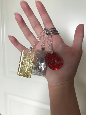 4 nyckelringar  - 4 helt nya nyckelringar av resin och en massa glitter med silveromfattning . Helt handgjorda och oanvända. Det är en i guld, silver, och två i röd. Skriv gärna vid fler bilder och funderingar. Har också fler smycken och nyckelringar på min profil🌺50kr st🌺