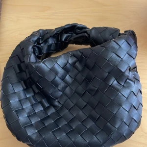 Bottega veneta Jodie leather handbag - Teen intrecciato leather shoulder bag • Single compartment  • Zip closure Material: 100% Lambskin • Lining: Calfskin • Color: Black • Hardware: Silver finish • Height: 21 cm | 8.2" • Width: 36 cm | 14.2" • Depth: 13 cm | 5.1" • Handle drop: 18 cm | 7.1" M