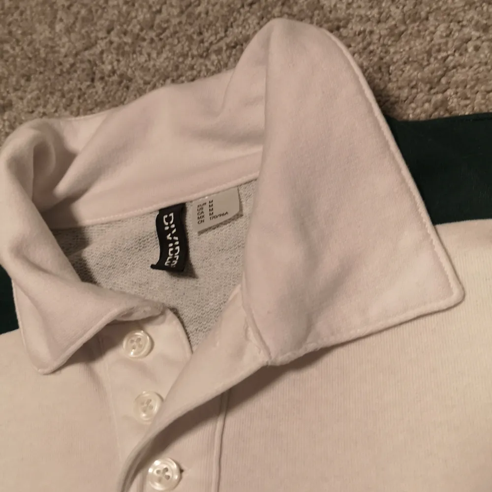 En supersnygg vit-och grönrandig tröja som är croppad och med krage. I storlek M från divided och i nyskick. Tröjor & Koftor.