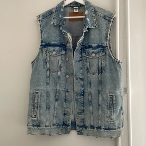H&M Denim väst strl S - Säljer denna stiliga denimväst från H&M då den inte blir använd. Använt bara ett fåtal gånger. Längre modell, storlek S men är oversized.