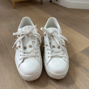 Valentino Rockstud Sneakers - Säljer mina vita Rockstud sneakers i storlek 38. Säljer pga använder dem ej längre och dem är i fint skick, endast lite skitiga på under sulan, men går att rengöra. Köpta på NK i Stockholm. Kommer med kvitto, box och extra skosnören! Inga byten 🤍