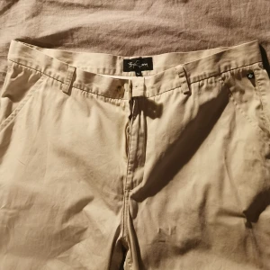 Byxa Björn Borg, vida i modellen, Stl 54 - Byxa bättre begagnad. Stl 54. Märke Björn Borg. Knäppning knapp och dragkedja. Beige till Creme färgade