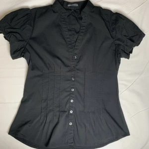 Svart topp - Söt kortärmad svart blus. Insydd midja och puffiga ärmar