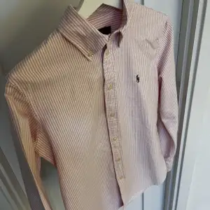 Randig Skjorta från märket Ralf Lauren. Säljer den för att den sitter för tajt. Det är storlek S, färgerna är vit och rosa. Jätte fin och i bra sick! Inga konstigheter😃 Priset är inte huggit i sten  Med vänlig hälsning, Oskar   