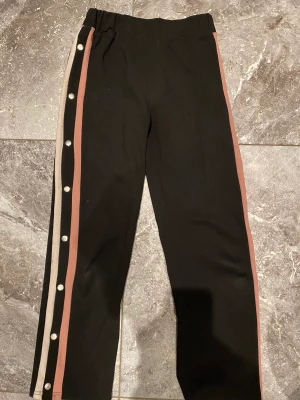 Mjukisbyxor stl.158/164 - Jättefina svarta mjukisbyxor med rosa linjedetaljer vid sidorna. Någorlunda noppriga. Storlek 158/164.Säljer pga stor garderobrensning. Kika gärna på mina andra annonser, säljer mycket. Samfraktar gärna:)