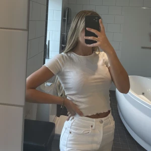 T-shirt vit - Vit t-shirt, lite kortare modell. Lite ribbad i materialet. Samt lite volanger vid ärmarna och längst ner. Storlek XS