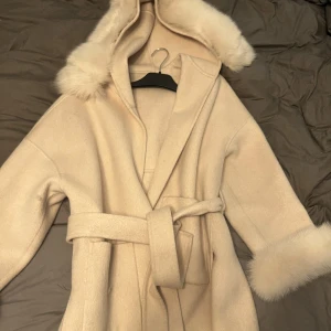 Pälskappa  - En beige kappa med päls på luvan och ärmarna, avtagbar. Använd fåtal gånger