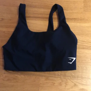 Gymshark top - En oanvänd gymshark svart sporttopp. Den är lite längre med en tyg som är matt. Sitter super bra och ser väldigt exklusiv ut