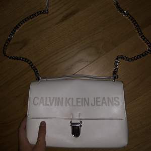 Handväska från Calvin Klein, använd kanske 5 gånger men ser ut som ny. Vit med grå text samt silverdetaljer.
