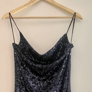 Oanvänd paljettklänning från Zara - Paljettklänning från Zara i magiskt midnattsblå färg, halvlång och asymmetrisk nederkant. Aldrig använd, storlek M