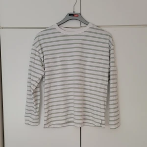 Randig topp - Vit/grön randig topp från Lager 157 i storlek s. Den är 54 cm lång från hals till midja. Armlängd från armhålan är ca. 42 cm. (Den är ganska lång på mig, men går att vika in som jag gjort på bilden.)