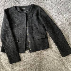 Svart kofta  - Fin svart kofta med instickat guldtråd vilket gör den lite guldig. Storlek 40 men skulle säga att den även passar strl 36.