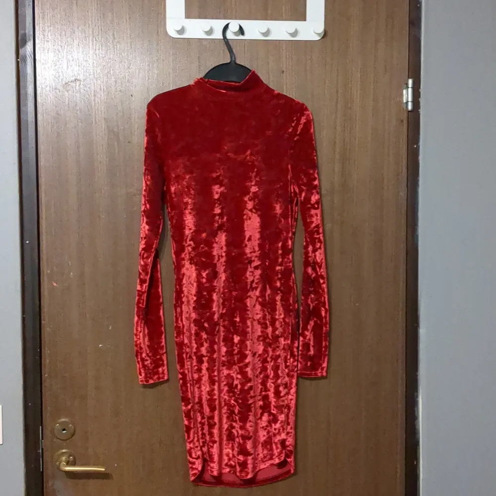 Röd klänning gjord av velour liknande material.. Klänningar.