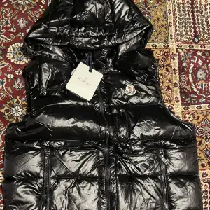 Moncler väst med luva i nyskick. Puff moncler väst med NFC skann, luva, i storlek L/3 och färgen svart. Västen är knapt använd i nyskick Fin matrial och topp kvalite Det är definitivt en ”en gångs deal”. Nypris 12000kr. Har du frågor, skriv görna till mig