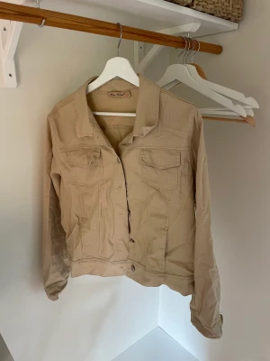 Jeansjacka - Beige/ljusbrun jacka i tunnt jeansmaterial. Ganska kort modell och lite liten i storleken men passar bra på m. 
