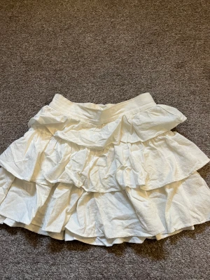 Vit kjol - Vit volangkjol från shein, inte använd mycket av mig men är köpt på plick, storlek xs, dragkedja på sidan, sitter väldigt tajt i midjan på mig:)