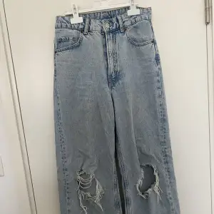 Blå vida jeans med hål som börjar bli för små.