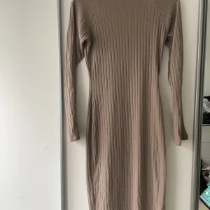 Klänning Bianca x Nelly - Mycket fin klänning Bianca x Nelly, säljs inte längre. Oanvänd, vara testad. Formar sig fint på kroppen dock aningen för kort för mig. Mauve/beige.