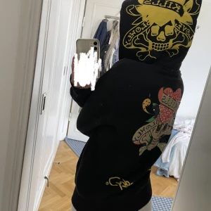 Ed Hardy hoodie - Den grejen på dragkedjan är av på hälften men själva dragkedjan fungerar fortfarande som den ska. Bortsett från det är hoodien i väldigt bra skick. På lappen står det strl L men passar mig som har Xs/S. Hittar inte just denna men en ny kostar ca 1300.