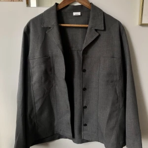 Stengrå tunn kavaj/jacka  - Denna vackra kavaj är i storlek L och i 100% polyester. Fint skick, köpt second hand men sedan dess aldrig använd🤍