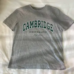 Jättecool Grå t-shirt från h&m med grönt tryck där det står ”Cambridge university”.🤘🏼 Den är från h&m i storlek XS. Fråga om frakt.