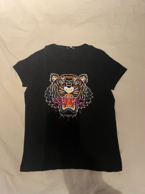 Kenzo Tshirt  - En svart kenzo Tshirt med ett färgglad tryck. Använd ett få tal gånger. Storlek S.