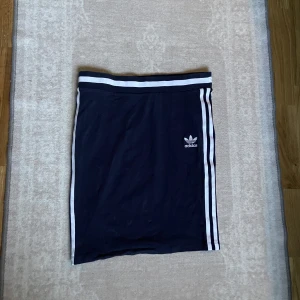 Blåvit Adidaskjol - En kjol från adidas, den är blå och vit och går nertill knäna. Köpt för 560kr