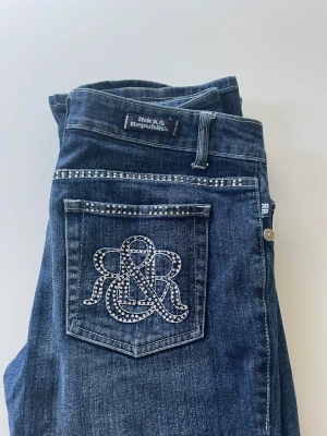 Rock & Republic jeans - Säljer mina fina bootcut/raka lågmidjade Rock & Republic jeans! Midja: 78cm, innerben: 80cm, ytterben: 103cm. Nyskick bortsett från att en del ”diamanter” har gått av, inget man tänker på enligt mig. Möts upp i Sthlm, annars står köparen för frakten 💜💕
