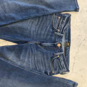 Lågmidjade Lee jeans med bootcut, hål på ena benet. Storlek W28 L33 passar S