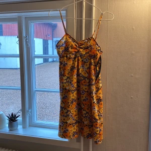 En blommig klänning  - Den har en dragkedja på sidan av klänningen. 