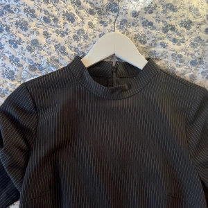 Klänning - Tajt svart svagt vit randig fodral klänning med högre hals.