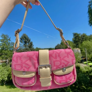 Rosa DKNY väska - Säljer min fantastiskt fina rosa vintage DKNY-väska!🤩 Perfekt till sommaren! Den är i jättefint skick, har enbart två välidgt små fläckar på baksidan (kan skicka bild om så önskas!  Hör av dig om du har några frågor! Kan skickas mot en fraktkostnad!☺️