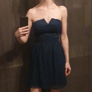 Oanvänd Elise Ryan-klänning - Mörkt marinblå miniklänning med spets över bysten. Supersnygg v-ringad kant överst! Axelbandslös. Stilren så går att kombinera med accessoarer för allehanda stilar! 😍  Endast provad, med lappar kvar.