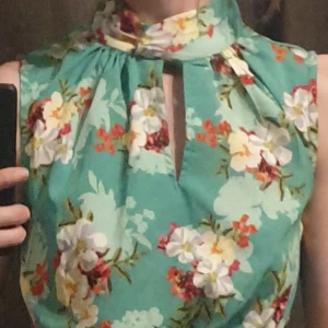 Blommig klänning från New look - Så fängslande färgglad så man Blir Glad! 🤗😍  Vacker grön klänning med blommigt mönster. Halvt hög krage och smock (heter det väl?) i midjan. Från New look.  Når till strax under knäna på mig som är 164 cm. Nyskick.