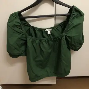 Mörkgrön topp från H&M i väldigt bra skick. Den är croppad, har puffärm och fyrkantig skärning. Storlek M, men kan även passa storlek L 💚